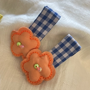 Detail of handmade orange fabric flower clips with colorful beads and plaid ribbon