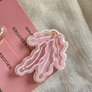 Dettaglio ravvicinato della molletta rosa in resina con trama a linee bianche