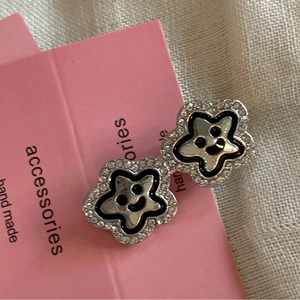 Star-shaped rhinestone hair clip with a black smiley face on pink card background
