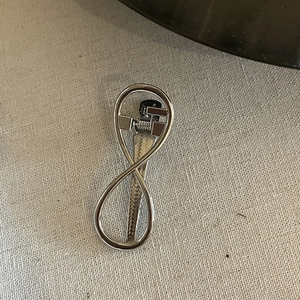 Close-up of minimalist silver infinity metal hair clip on white textured fabric background
