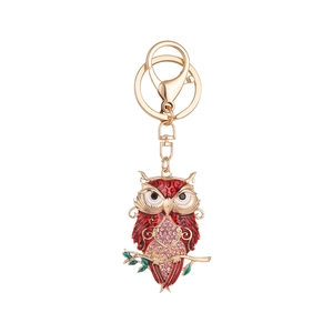Golden owl keychain with red enamel and pink rhinestones on a white background
