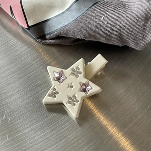 Star-shaped hair clip with pink and clear rhinestones on cream base, overhead view