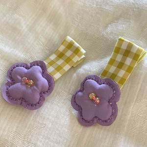 Close-up of candy-colored floral hair clips with yellow plaid ribbon and pearls