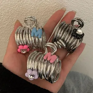 Detail of floral hair claw clips with M letter and crystals in multiple colors