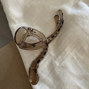 Close-up of translucent brown leopard print hair claw clip with golden metal spring