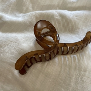 Close-up of translucent amber brown hair claw clip with twisted design on white fabric