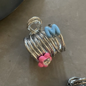 Silver metal flower hair claw clip with blue letter M and pink floral detail