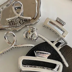 Set of assorted silver metallic hair claws in geometric cross and hollow rectangle styles