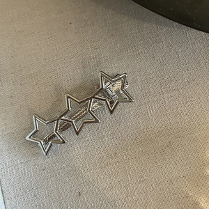 Detailed view of silver metallic hair clip featuring three hollow star-shaped patterns