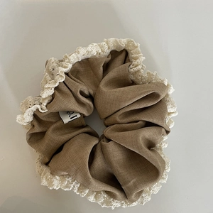 Detail of coffee brown scrunchie with cream lace edge and internal brand label