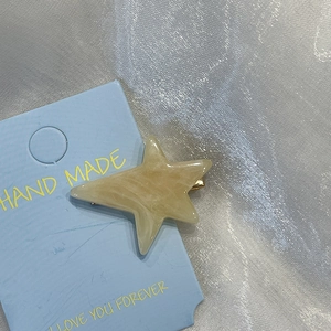 Dettaglio di fermaglio per capelli a stella crema marmorizzato su base azzurra