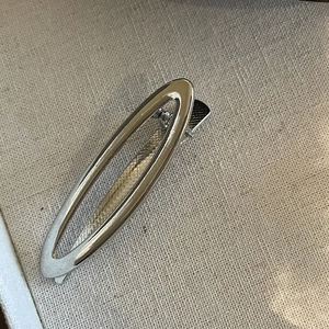 Macro view of silver hollow oval metal hair clip with non-slip duckbill spring grip