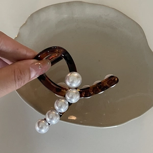 Dettaglio del fermaglio per capelli tartarugato con sei eleganti perle bianche a onda