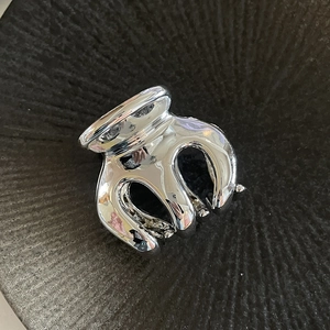 Detailed top view of a large silver hair claw clip with a polished mirror finish on gray tray