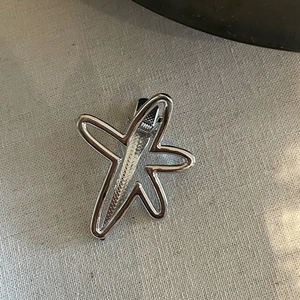 Detailed view of silver metallic star hair clip with non-slip duckbill grip back