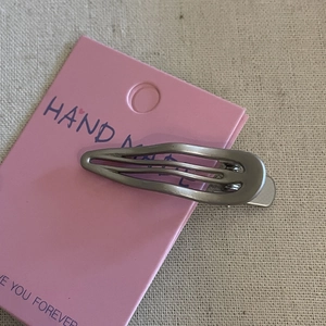 Silver metallic teardrop hair clip on pink card with handmade lettering detail