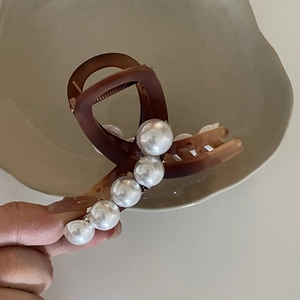 Dettaglio della molletta per capelli marrone opaco con perle finte bianche sfumate