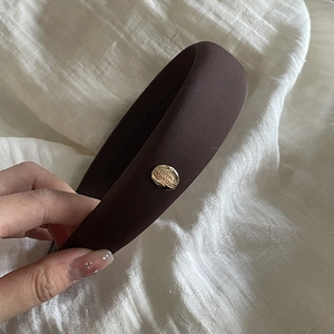 Detail of sponge headband with gold circular metal piece engraved Believe in Yourself