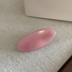 Detail view of pink oval acetate hair clip with golden France handmade lettering on fabric