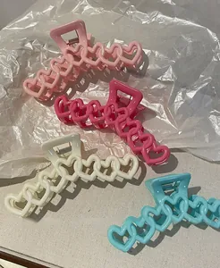 Dettaglio di mollette per capelli a cuore cavo in rosa, fucsia, crema e azzurro