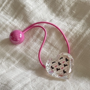 Détail de l'élastique à cheveux rose avec cœur en acrylique et motif de lapin