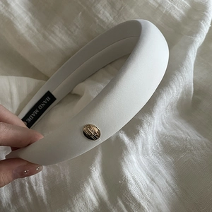 Detail of white padded headband featuring a gold buckle with Believe in Yourself text