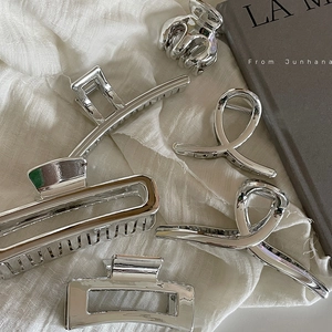 Five-piece silver shark hair clip set with metallic finish on white fabric and books