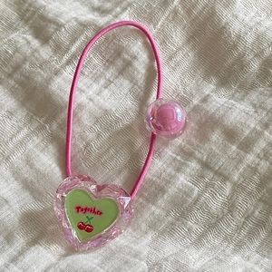 Détail d'un élastique rose avec pendentif coeur en cristal et motif cerise mignon