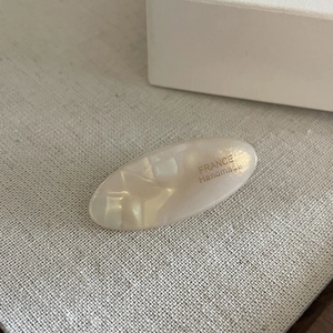 Macro shot of oval acetate hair clip with marble texture and France Handmade text