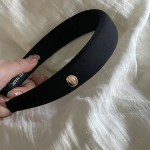 Close-up of black sponge headband with gold buckle and handmade woven fabric texture