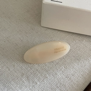 Close-up of beige acetate oval hair clip with France Handmade lettering detail