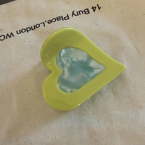 Close-up of heart-shaped acetate hair claw clip with yellow frame and blue pearlescent center