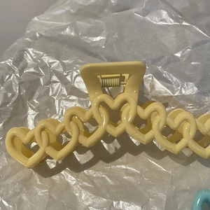 Dettaglio del fermaglio per capelli giallo a forma di cuore con molla in metallo