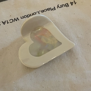 Elegant heart-shaped acetate hair claw clip with colorful marble pattern on beige fabric