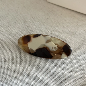 Macro shot of oval acetate hair clip with tortoise shell pattern and France Handmade logo
