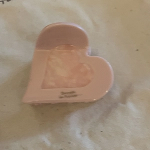 Detailed view of a pink heart-shaped acetate hair claw with glossy French style finish