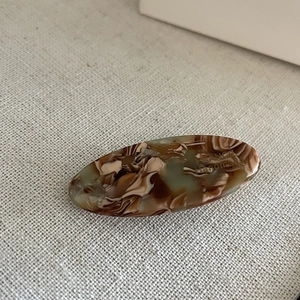 Detail of handmade oval marble pattern acetate hair clip with engraved lettering