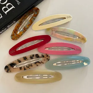 Set of eight colorful oval acetate hair clips in assorted marble patterns on a white background