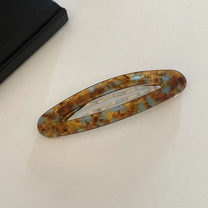 Oval acetate hair clip with blue and amber marble pattern and silver spring clasp