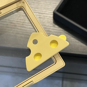 Macro d'une pince à cheveux fromage jaune montrant la texture des trous et la finition plastique