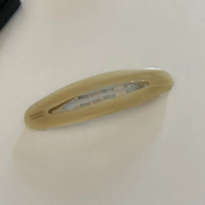 Close-up of a creamy yellow oval acetate hair clip with a minimalist hollowed-out center
