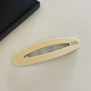 Detailed close-up of beige oval acetate hair clip with Barrette La France gold lettering