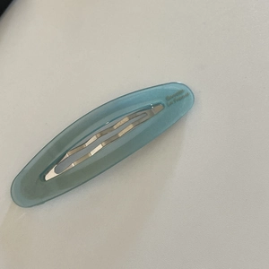 Macro detail of translucent blue acetate oval hair clip showing gold Barrette lettering