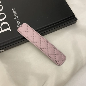 Détail rapproché d'une barrette en cuir rose avec motif élégant de losanges surpiqués
