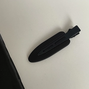 Detail shot of a matte black hair clip showing the smooth frosted surface and grip design