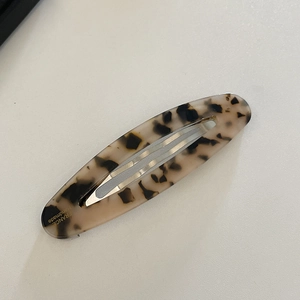 Detailed macro view of an oval acetate hair clip featuring a classic leopard print pattern