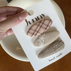 Detailed set of brown fabric bow hair clips with embroidery and lace on a display card