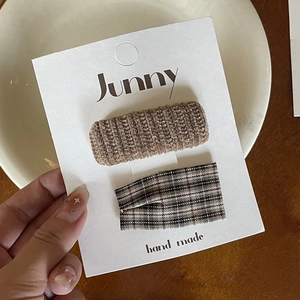Detail shot of brown knit and plaid fabric bow hair clips on a white display card