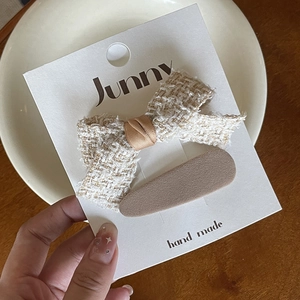 Detail of handmade cream tweed bow and coffee brown fabric hair clips on card