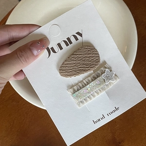 Detail of handmade bow hair clips with embroidery and beige ruffles on display card